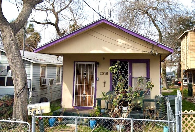 bungalow-style house with a fenced front yard, cooling unit, a gate, and stucco siding