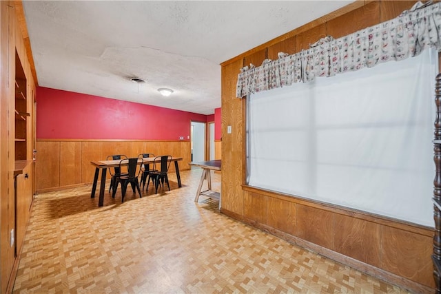 dining room featuring parquet floors, a textured ceiling, and wooden walls