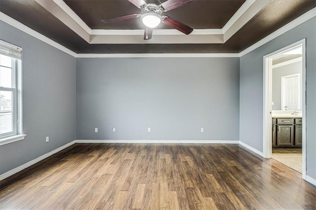 unfurnished room with plenty of natural light, a raised ceiling, and dark wood-style flooring