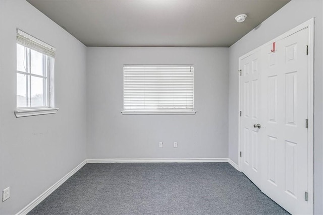 unfurnished bedroom with baseboards and dark colored carpet