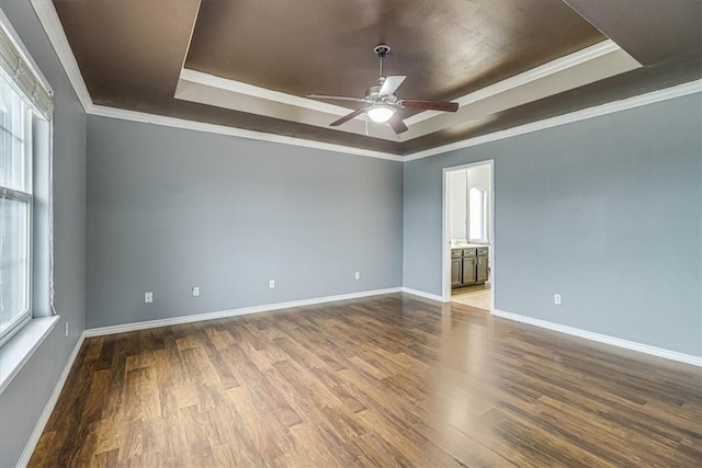 unfurnished room with plenty of natural light, a raised ceiling, and wood finished floors