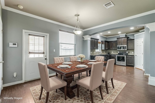 dining area featuring crown molding, visible vents, dark wood finished floors, and baseboards