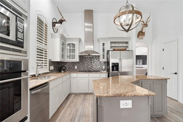 4589 Teal Dr, Corpus Christi, TX 78410 - kitchen featuring light wood-type flooring, wall chimney range hood, a kitchen island, a sink, and stainless steel appliances