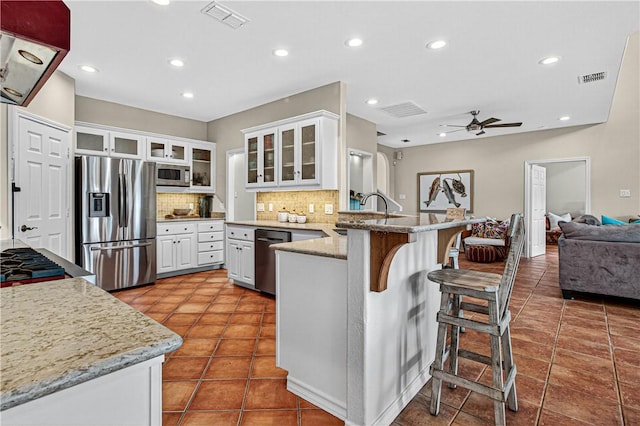 973 Pompano Dr, Aransas Pass, TX 78336 - kitchen featuring stainless steel appliances, a peninsula, ceiling fan, exhaust hood, and tasteful backsplash