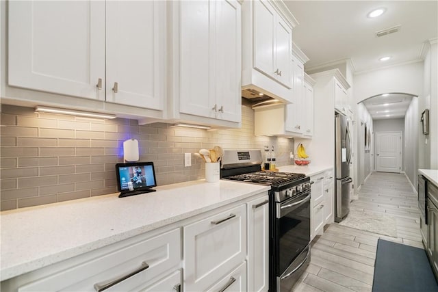 6421 Aikman, Corpus Christi, TX 78414 - kitchen with appliances with stainless steel finishes, arched walkways, white cabinets, ornamental molding, and light wood-type flooring