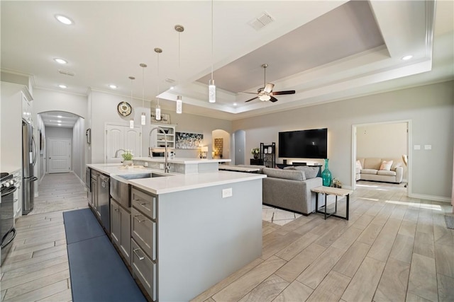 6421 Aikman, Corpus Christi, TX 78414 - kitchen with arched walkways, a ceiling fan, light countertops, a raised ceiling, and light wood-type flooring