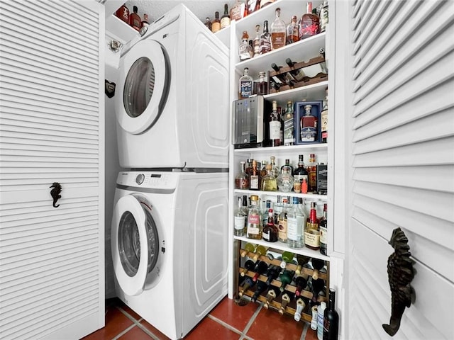 washroom with tile patterned flooring and stacked washing maching and dryer