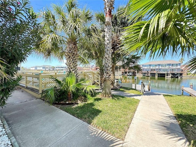 surrounding community with a water view, a yard, and a boat dock