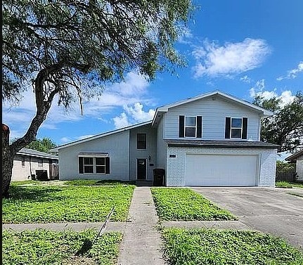 split level home with an attached garage, a front yard, and aphalt driveway