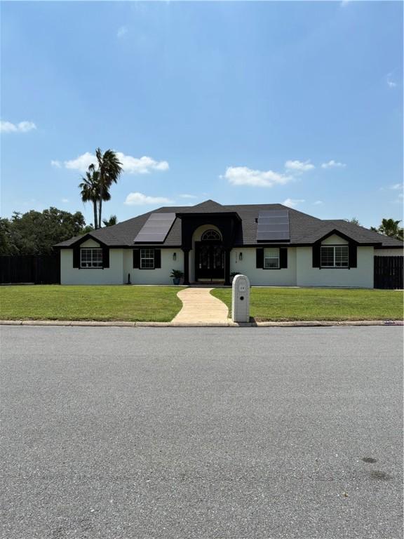 view of front facade with roof mounted solar panels and a front lawn