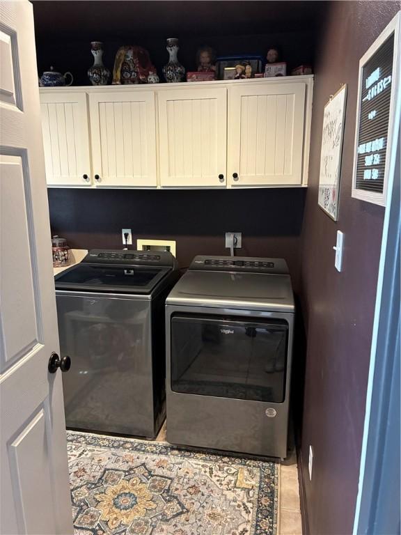 laundry area featuring cabinet space, washer and clothes dryer, and light tile patterned flooring