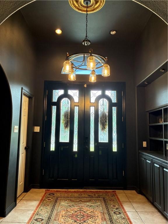 entryway featuring light tile patterned flooring, arched walkways, recessed lighting, and a chandelier