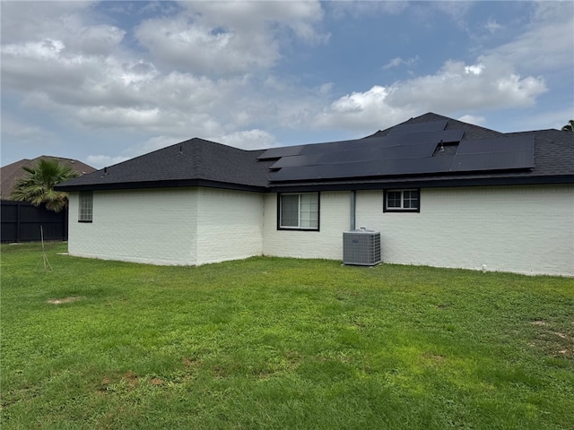 back of property featuring central AC unit and roof mounted solar panels