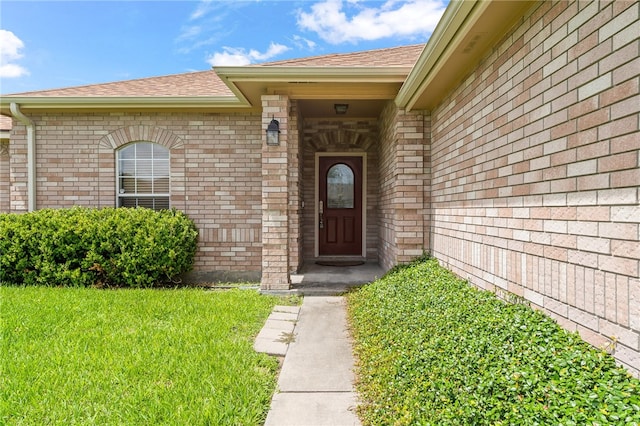 4241 Aaron Cv, Corpus Christi, TX 78413 - view of exterior entry featuring a shingled roof, brick siding, and a lawn