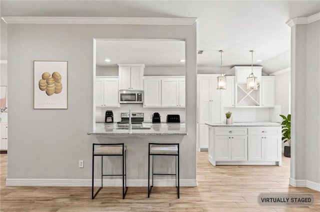 4241 Aaron Cv, Corpus Christi, TX 78413 - kitchen featuring appliances with stainless steel finishes, backsplash, light wood-style floors, white cabinets, and a kitchen breakfast bar