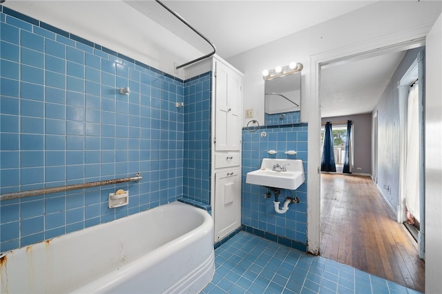 bathroom featuring hardwood / wood-style floors, tiled shower / bath, tile walls, and sink