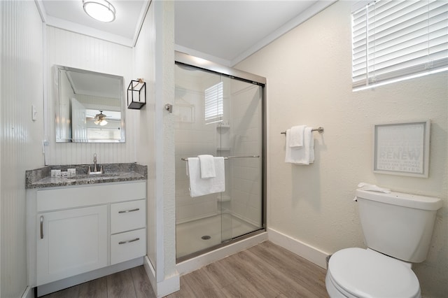 bathroom with ornamental molding, ceiling fan, wood-type flooring, toilet, and a shower with shower door