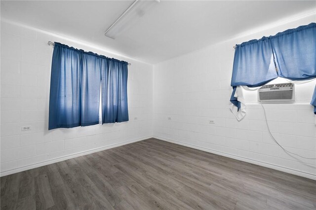 217 E Brundrett Ave, Port Aransas, TX 78373 - spare room with wood finished floors, cooling unit, and concrete block wall