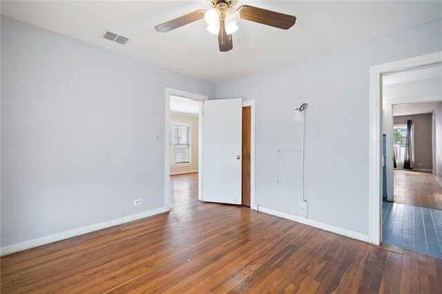 217 E Brundrett Ave, Port Aransas, TX 78373 - unfurnished bedroom featuring multiple windows, baseboards, wood finished floors, and ceiling fan