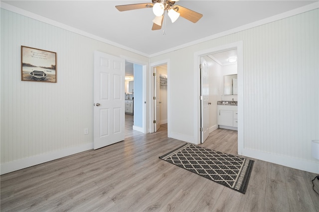 interior space featuring ensuite bathroom, ornamental molding, ceiling fan, sink, and light hardwood / wood-style flooring