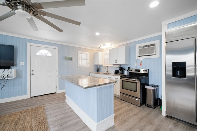 kitchen featuring white cabinets, a wall unit AC, appliances with stainless steel finishes, and light hardwood / wood-style flooring