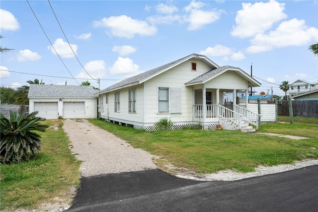 view of front of home with a porch, a garage, an outbuilding, and a front yard