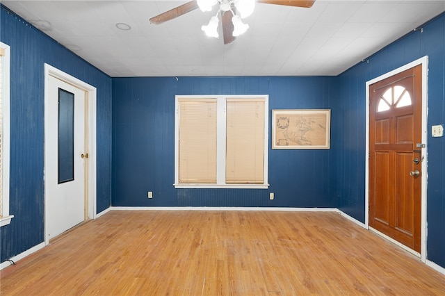 entryway with light hardwood / wood-style flooring, ceiling fan, and wood walls