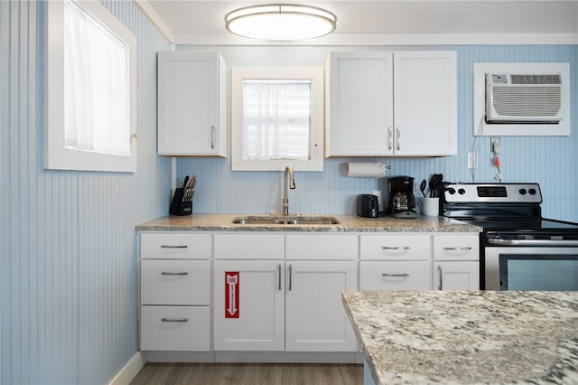 kitchen with stainless steel electric range oven, sink, light hardwood / wood-style flooring, an AC wall unit, and white cabinets