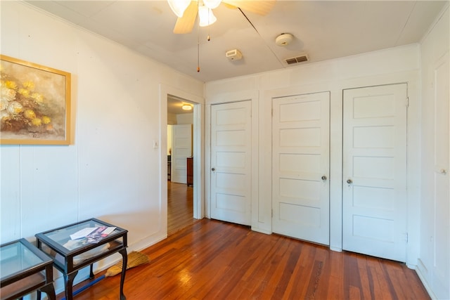 bedroom with dark wood-type flooring, ceiling fan, and crown molding