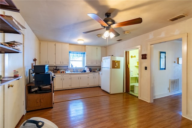 kitchen featuring hardwood / wood-style flooring, sink, ceiling fan, white fridge, and white cabinetry