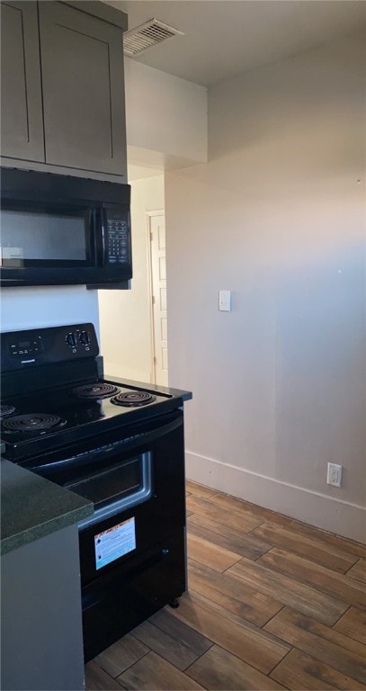 kitchen featuring gray cabinets, dark hardwood / wood-style flooring, and black appliances