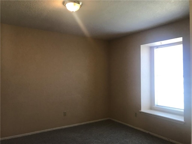 empty room featuring baseboards and dark carpet