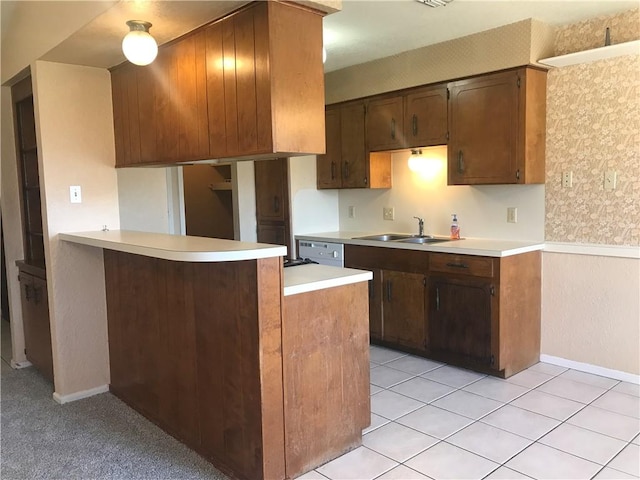 kitchen with a peninsula, light countertops, a sink, and light tile patterned flooring