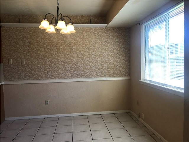 unfurnished dining area with a chandelier, wainscoting, tile patterned flooring, and baseboards