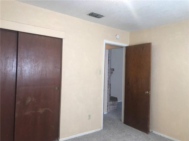 unfurnished bedroom featuring light carpet, a closet, visible vents, and baseboards