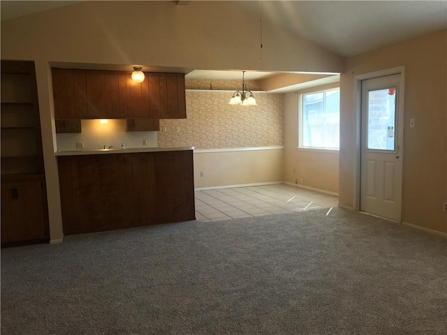 kitchen with lofted ceiling, light tile patterned flooring, light colored carpet, an inviting chandelier, and wallpapered walls