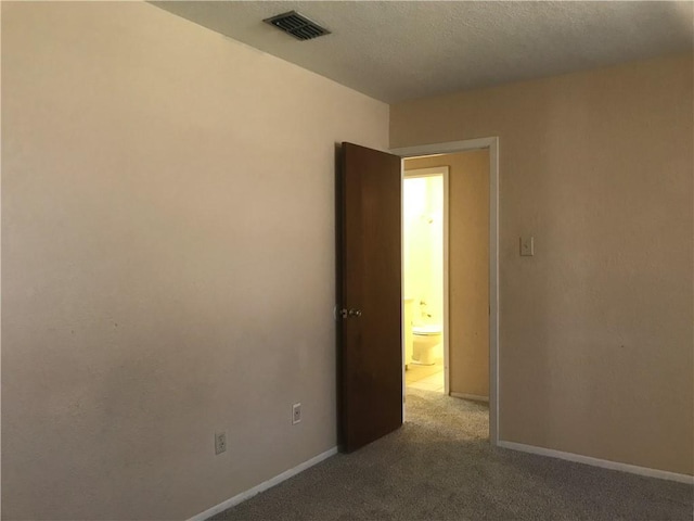 carpeted spare room featuring visible vents and baseboards