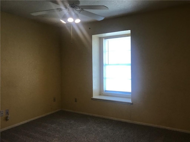 unfurnished room with ceiling fan, baseboards, and dark colored carpet