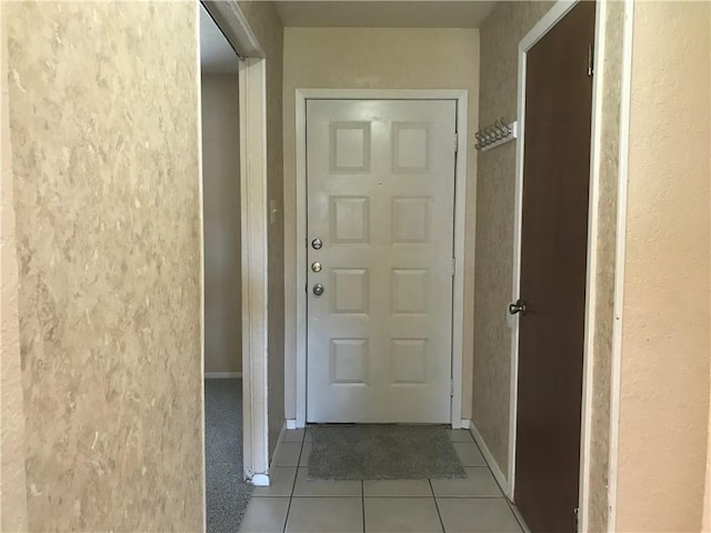 doorway with tile patterned flooring and baseboards