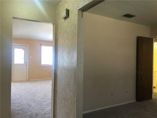 hallway with carpet flooring, visible vents, and baseboards