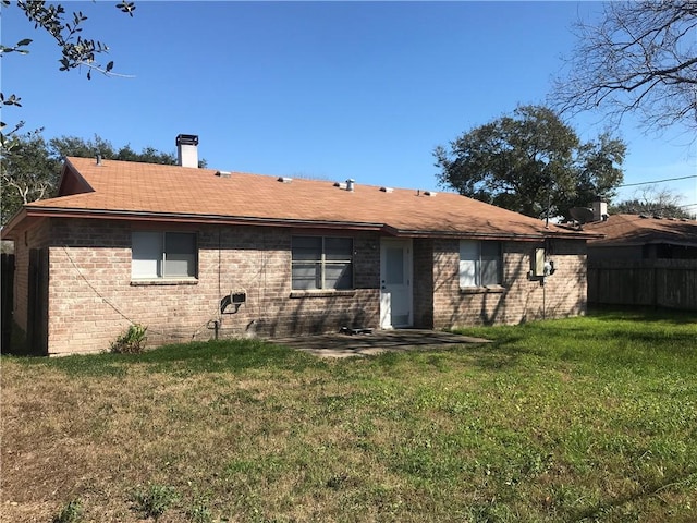 rear view of property featuring a patio area, a lawn, brick siding, and fence