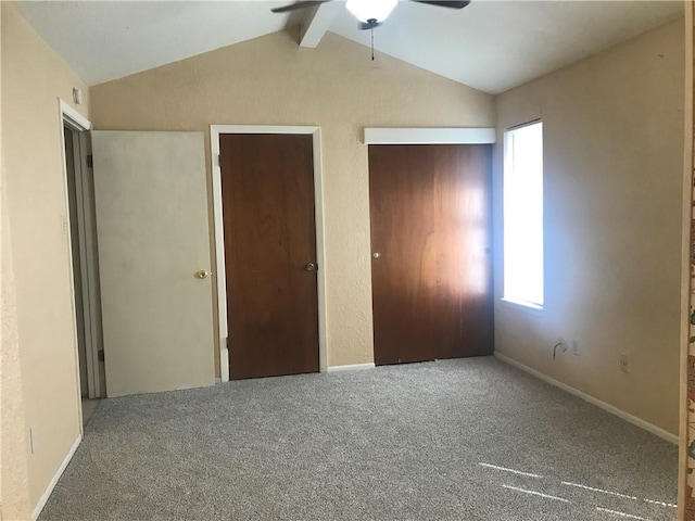 unfurnished bedroom with lofted ceiling with beams, carpet, and baseboards