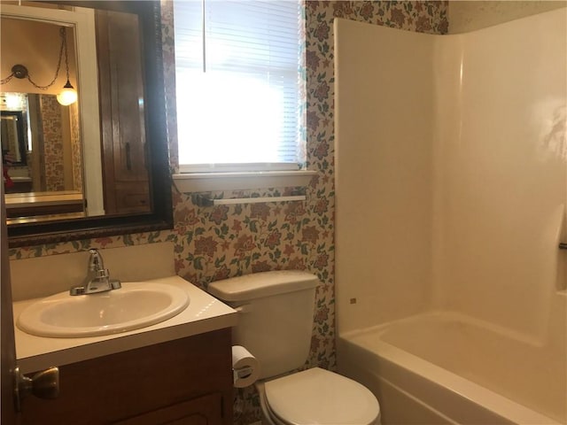 full bathroom featuring toilet, wallpapered walls, washtub / shower combination, and vanity