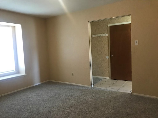 unfurnished room featuring light carpet, light tile patterned floors, and baseboards