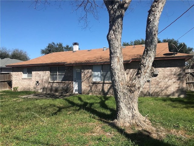 rear view of house with brick siding, fence, and a yard