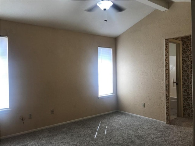 carpeted spare room featuring vaulted ceiling with beams, a textured wall, a wealth of natural light, and a ceiling fan