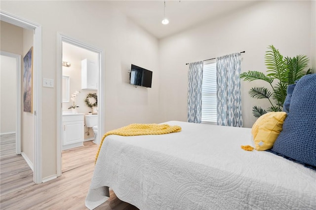 bedroom featuring baseboards, ensuite bath, and light wood finished floors