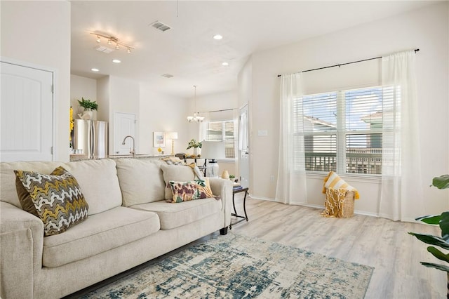 living room with visible vents, baseboards, light wood-style flooring, recessed lighting, and a notable chandelier