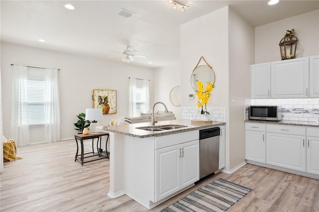 kitchen featuring a sink, a peninsula, a healthy amount of sunlight, and stainless steel appliances