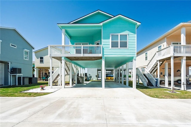 raised beach house featuring a carport, stairway, and driveway